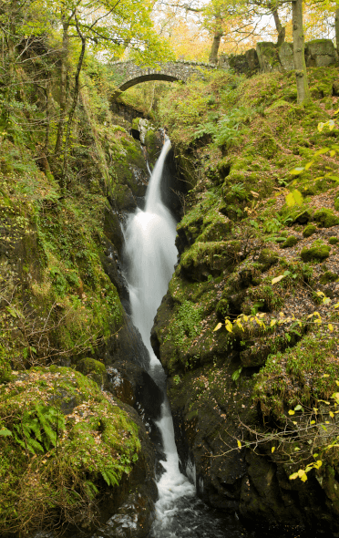 Aira Force, a waterfall in the Lake District that tumbles seventy feet between these two mossy rocks into the pool below.